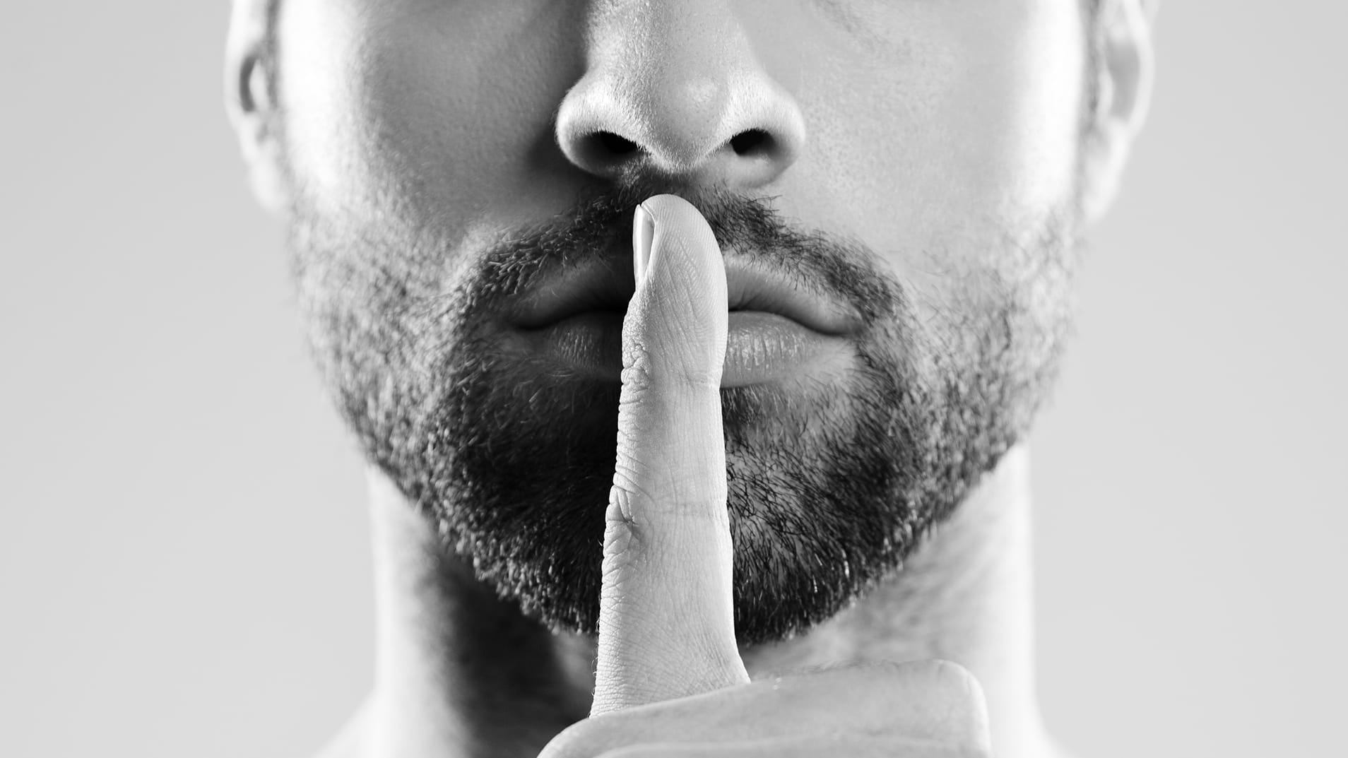 Portrait of a young charming naked man showing silence gesture